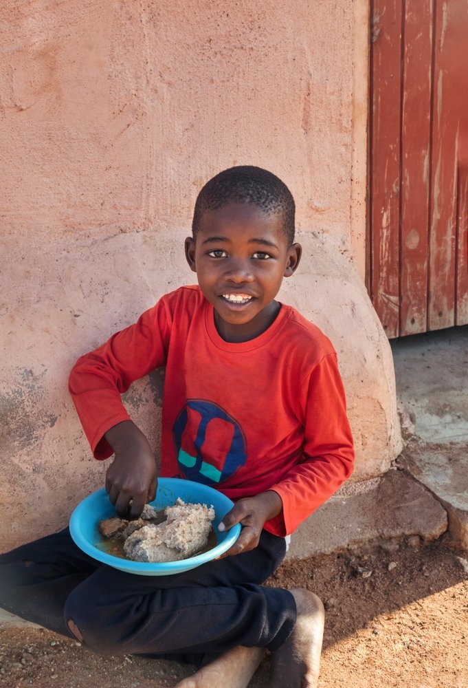 Small,African,Child,Eating,On,The,Ground,A,Plate,Of
